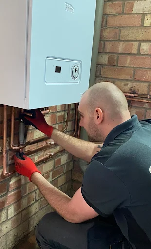 Emergency plumber repairing pipework beside a boiler